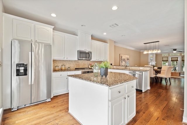 kitchen with a kitchen island, light stone countertops, light wood-type flooring, a peninsula, and stainless steel appliances