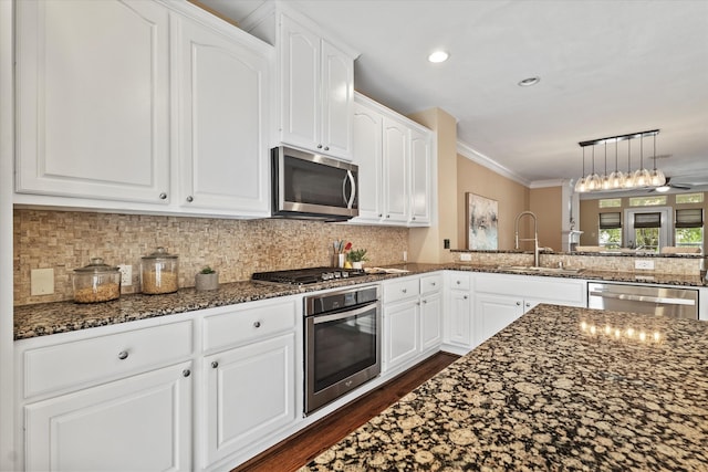 kitchen featuring appliances with stainless steel finishes, a sink, white cabinets, dark stone countertops, and dark wood-style floors