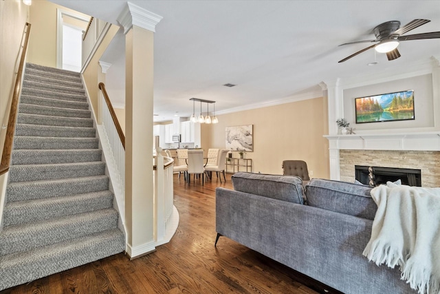 living area with crown molding, ceiling fan with notable chandelier, stairs, and dark wood finished floors