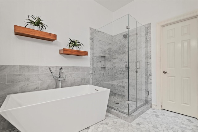 bathroom with a freestanding tub, tile walls, and a shower stall