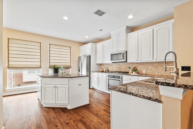 kitchen with visible vents, a sink, dark stone countertops, and appliances with stainless steel finishes
