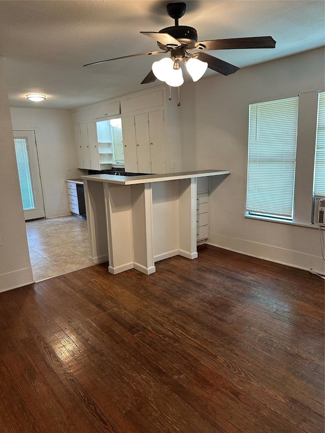 630 W College St, Stephenville, TX 76401 - kitchen with hardwood / wood-style floors, ceiling fan, baseboards, white cabinetry, and a peninsula