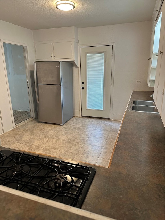 630 W College St, Stephenville, TX 76401 - kitchen with freestanding refrigerator, a sink, and white cabinetry