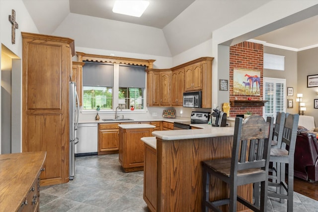 kitchen featuring brown cabinetry, vaulted ceiling, a sink, light countertops, and stainless steel appliances