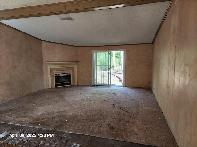 unfurnished living room with a tiled fireplace, vaulted ceiling, a textured ceiling, and visible vents