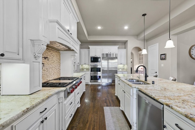 kitchen featuring a sink, built in appliances, and white cabinets