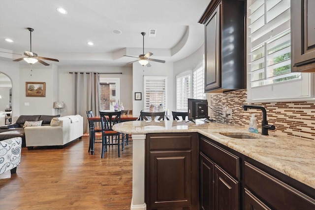 kitchen with ceiling fan, backsplash, wood finished floors, and dark brown cabinets
