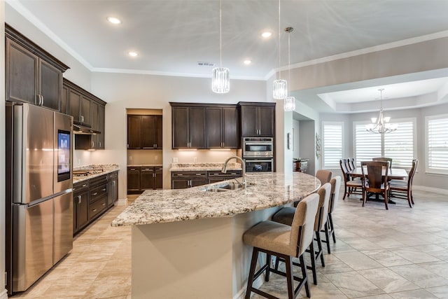 kitchen with dark brown cabinetry, a notable chandelier, appliances with stainless steel finishes, a sink, and under cabinet range hood