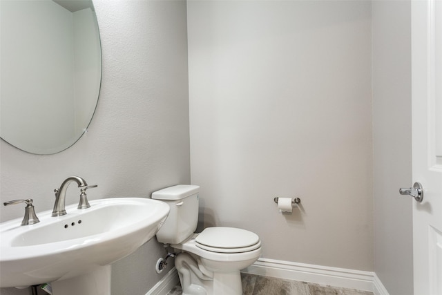 bathroom with a sink, baseboards, and toilet