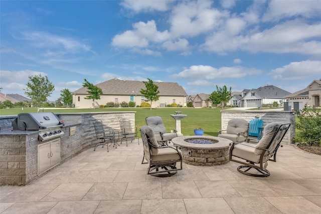 view of patio featuring area for grilling, exterior kitchen, a residential view, and a fire pit