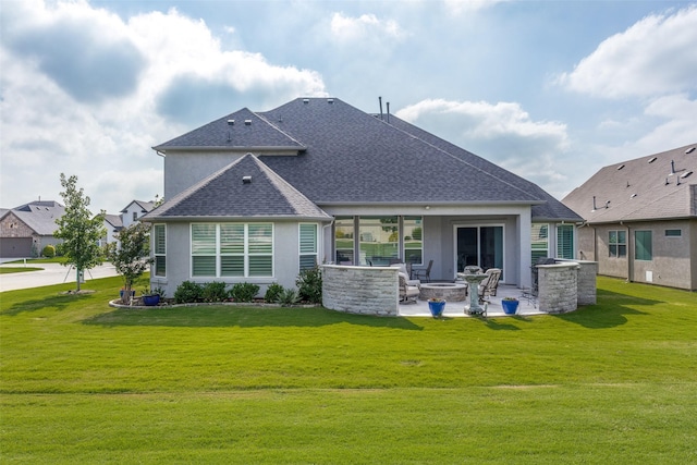 rear view of house featuring a patio, a shingled roof, an outdoor fire pit, and a yard