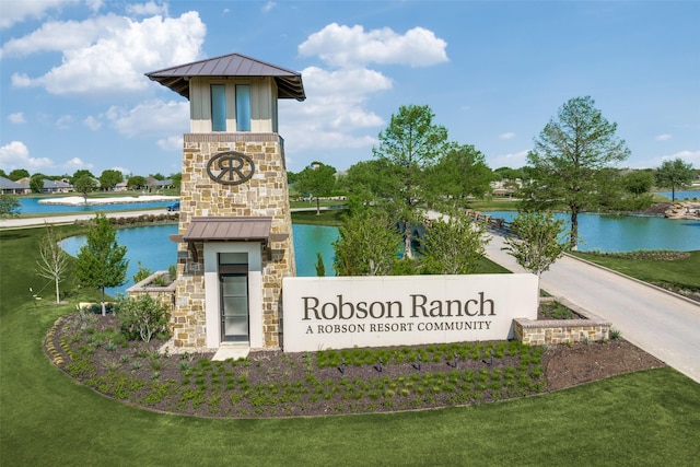 community / neighborhood sign with a lawn and a water view