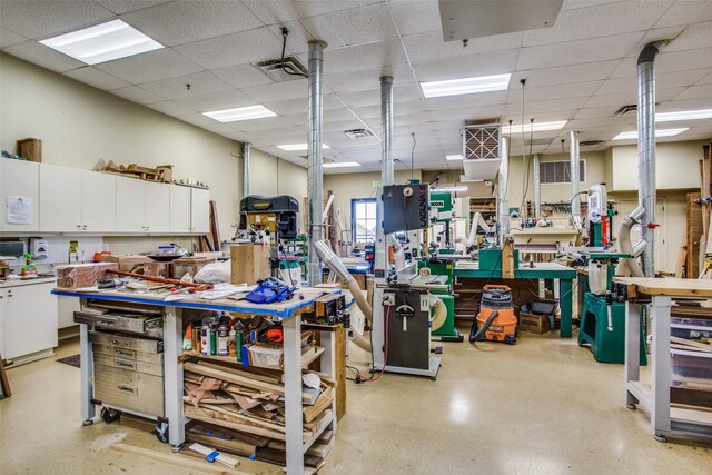 miscellaneous room with a workshop area, a drop ceiling, and visible vents