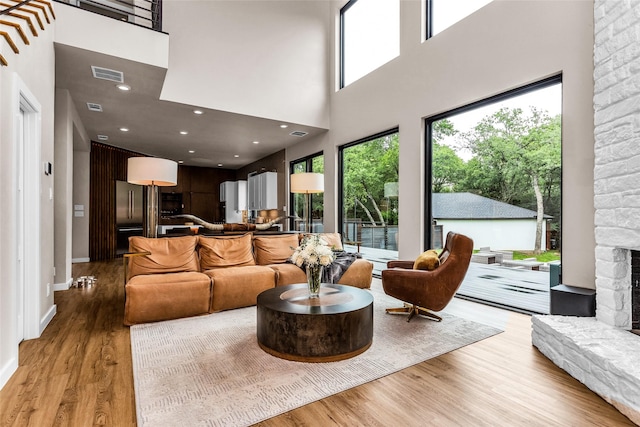 2856 Peninsula Dr, Grapevine, TX 76051 - living area with light wood-style floors, visible vents, a stone fireplace, and a towering ceiling
