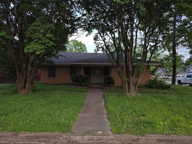 view of front of property with brick siding, roof with shingles, and a front yard