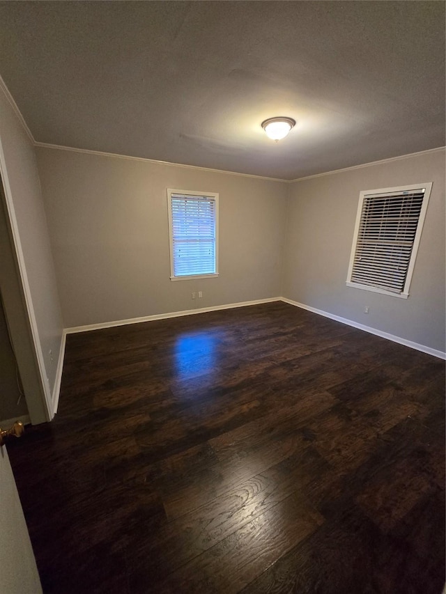 unfurnished room featuring dark wood-type flooring, ornamental molding, baseboards, and visible vents