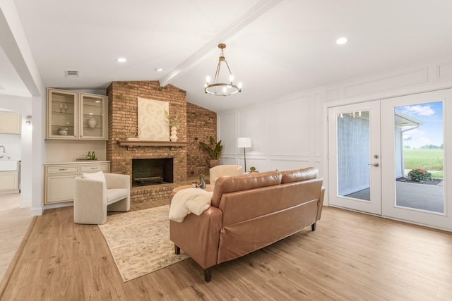 1004 Meridith Dr, Terrell, TX 75160 - living area with french doors, a brick fireplace, light wood-type flooring, a notable chandelier, and vaulted ceiling with beams