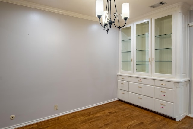 2103 Juanita Dr, Arlington, TX 76013 - unfurnished dining area featuring crown molding, a notable chandelier, baseboards, wood finished floors, and visible vents
