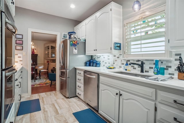 kitchen with light countertops, appliances with stainless steel finishes, white cabinets, and tasteful backsplash