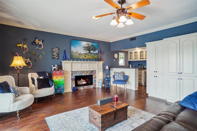 living area with visible vents, ornamental molding, dark wood-type flooring, and ceiling fan