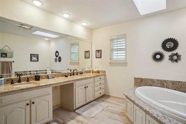 full bath featuring double vanity, a sink, a garden tub, and a skylight
