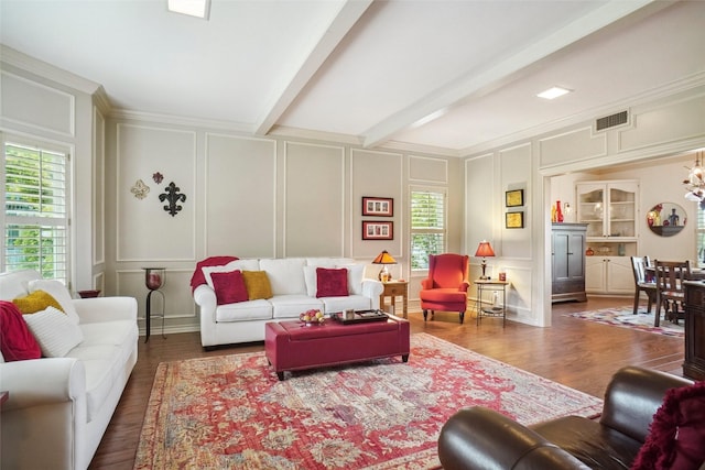 living room with visible vents, plenty of natural light, wood finished floors, and a decorative wall