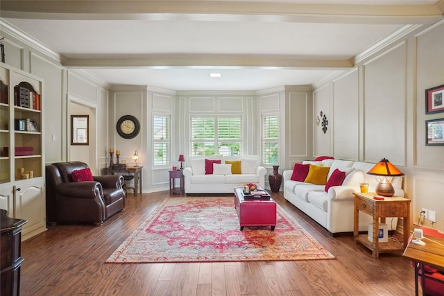 living area with wood finished floors, ornamental molding, a decorative wall, and beamed ceiling
