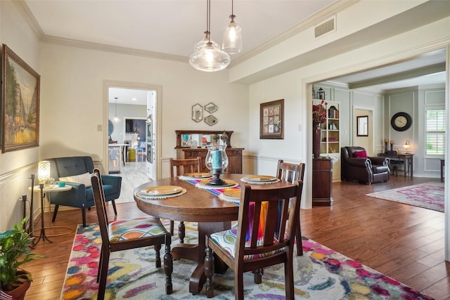dining area featuring crown molding, hardwood / wood-style floors, and visible vents