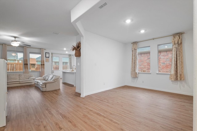 unfurnished living room with ceiling fan, light wood finished floors, visible vents, and a wealth of natural light