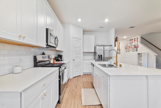 kitchen with visible vents, a sink, light countertops, white cabinets, and stainless steel appliances