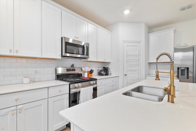 kitchen with light countertops, a sink, white cabinets, and stainless steel appliances