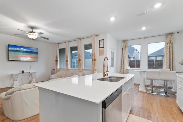 kitchen featuring stainless steel dishwasher, visible vents, open floor plan, a sink, and light wood finished floors