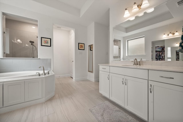 bathroom with a walk in closet, visible vents, baseboards, vanity, and tiled shower