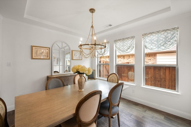 dining area with a notable chandelier, a raised ceiling, baseboards, wood finished floors, and visible vents