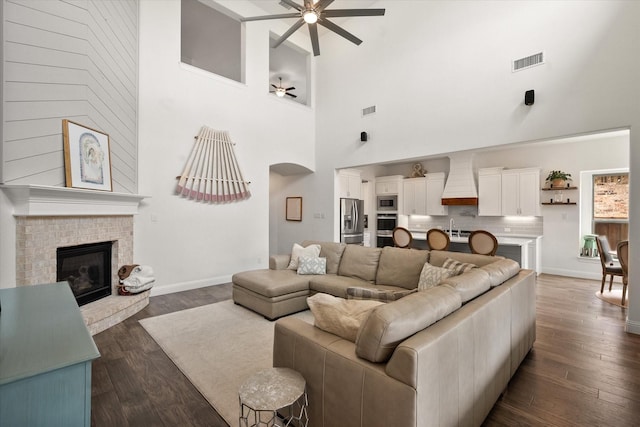 living room featuring a towering ceiling, a ceiling fan, arched walkways, and visible vents