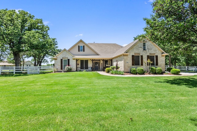 view of front facade with fence, stone siding, and a front yard