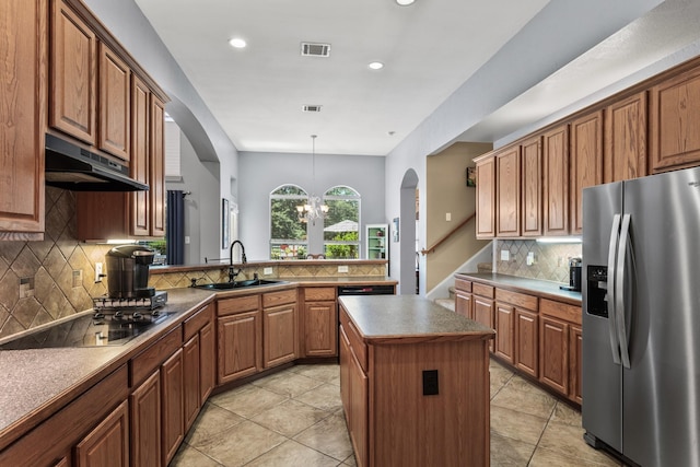kitchen with black cooktop, a sink, stainless steel refrigerator with ice dispenser, arched walkways, and under cabinet range hood