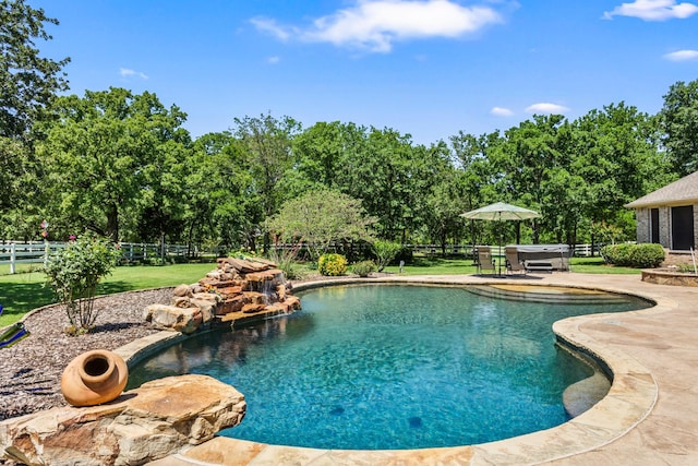 outdoor pool featuring a hot tub, view of scattered trees, and a patio