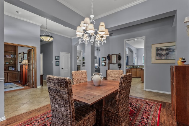 dining room with ornamental molding, a notable chandelier, light wood-style floors, and baseboards