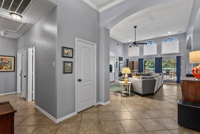 interior space with a towering ceiling, attic access, tile patterned floors, arched walkways, and baseboards