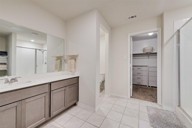 bathroom with a walk in closet, visible vents, a shower stall, vanity, and tile patterned floors