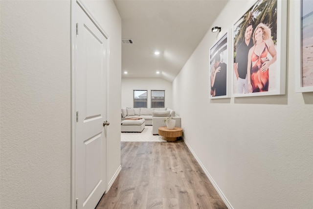 corridor featuring visible vents, vaulted ceiling, wood finished floors, baseboards, and recessed lighting