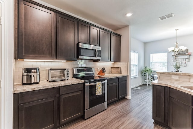 3225 Sweetwater Way, Sherman, TX 75090 - kitchen with visible vents, wood finished floors, dark brown cabinets, backsplash, and stainless steel appliances