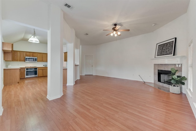 unfurnished living room featuring visible vents, a ceiling fan, light wood finished floors, and a tiled fireplace