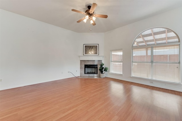 unfurnished living room featuring baseboards, light wood-style floors, ceiling fan, and a tile fireplace