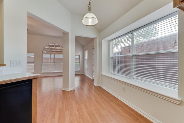 foyer entrance featuring baseboards, vaulted ceiling, and light wood-style flooring