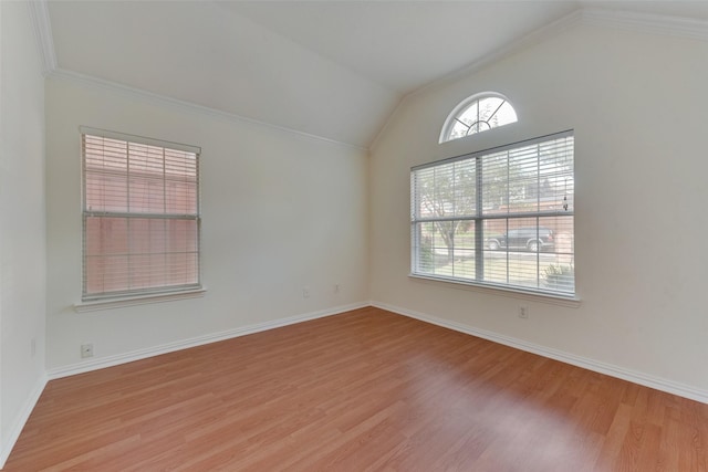 spare room featuring light wood-style floors, baseboards, crown molding, and vaulted ceiling
