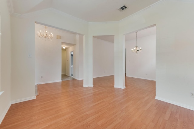 spare room with baseboards, an inviting chandelier, light wood-style flooring, and visible vents