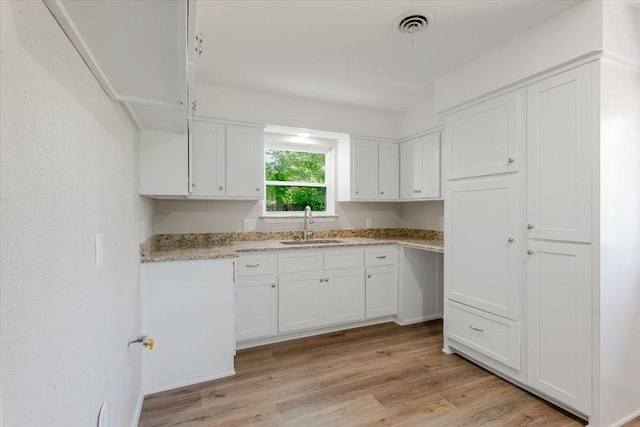 1017 SE 21st St, Mineral Wells, TX 76067 - kitchen featuring light wood-style floors, a sink, white cabinetry, and visible vents