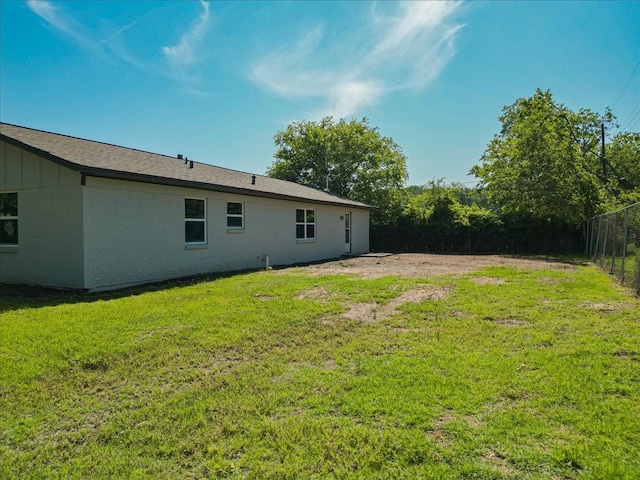 1017 SE 21st St, Mineral Wells, TX 76067 - rear view of house with board and batten siding, a lawn, and fence